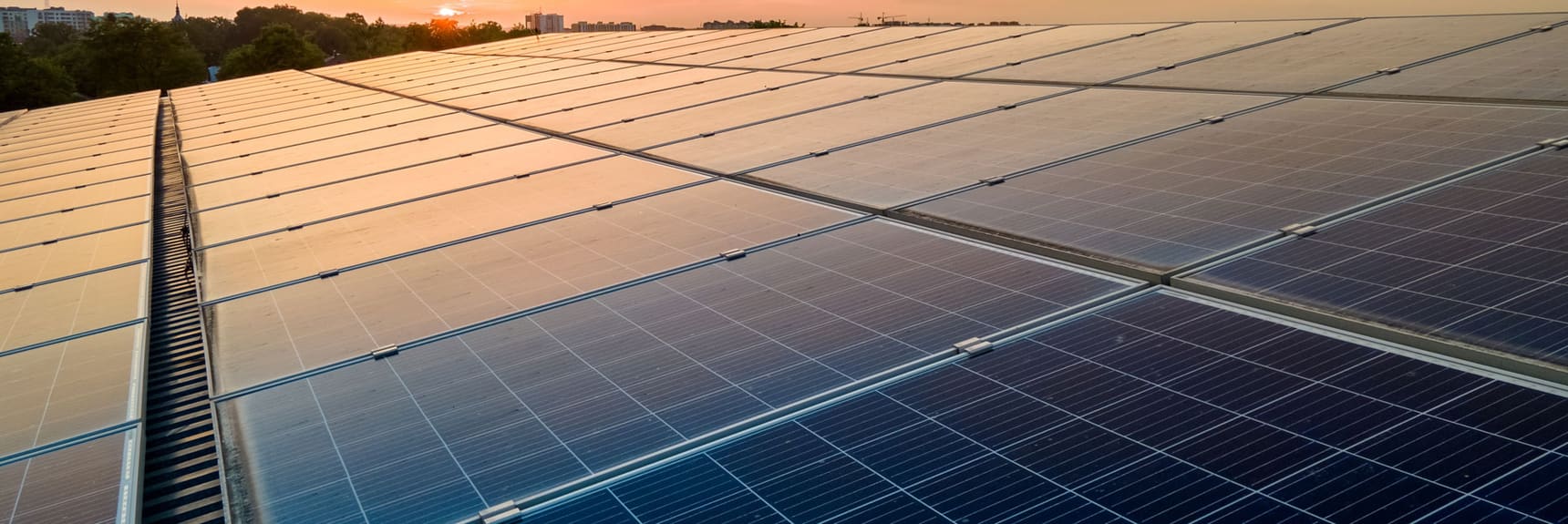Solar panels silhouetted against a sunset sky